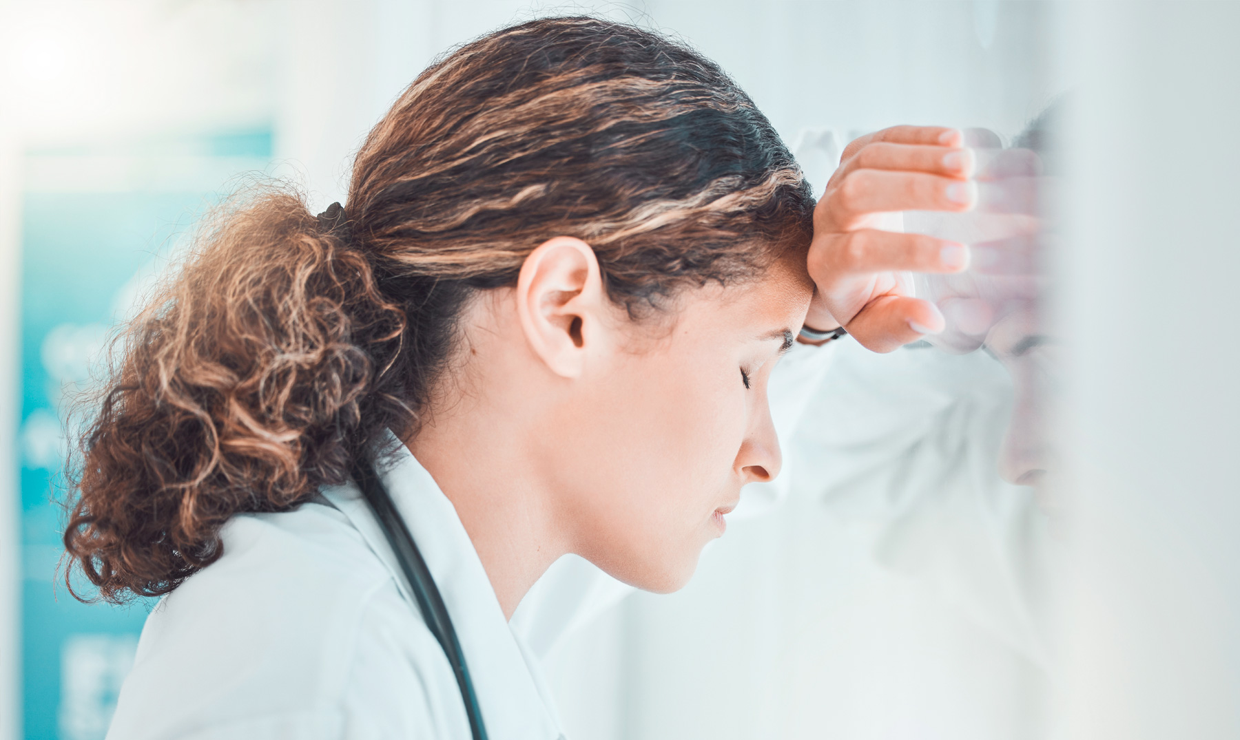 Female doctor resting head in against window