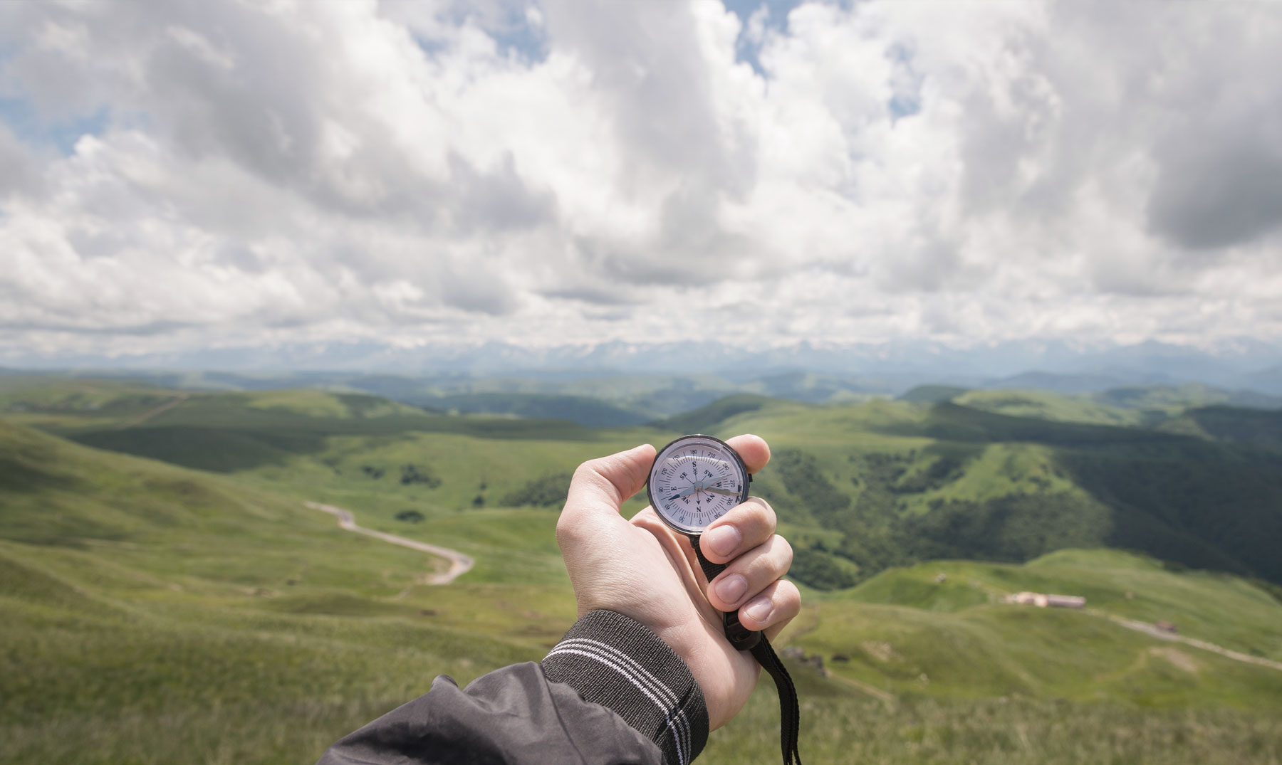 hand with compass and mountian range